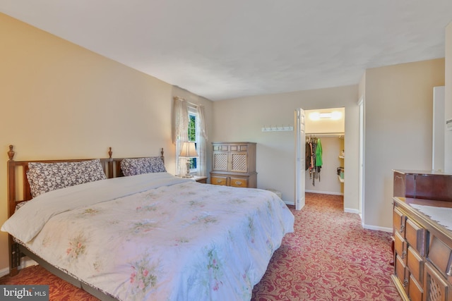 bedroom with baseboards, a spacious closet, a closet, and light colored carpet
