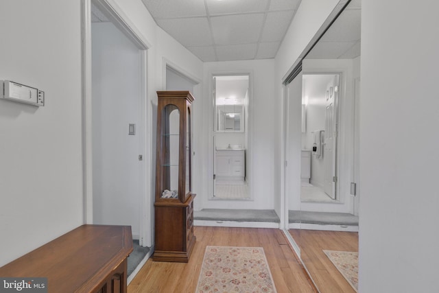 interior space with baseboards, a paneled ceiling, and light wood-style floors