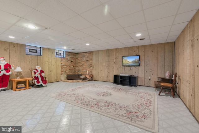 interior space with tile patterned floors, a drop ceiling, and wood walls