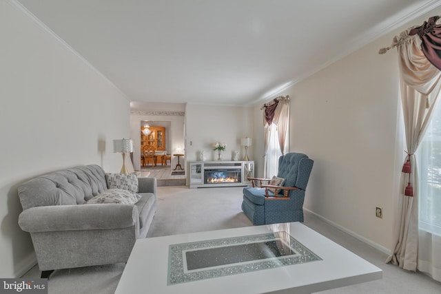 living room featuring baseboards, a glass covered fireplace, light carpet, and ornamental molding