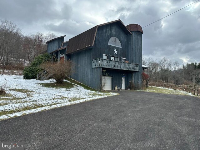 snow covered structure with a garage and driveway
