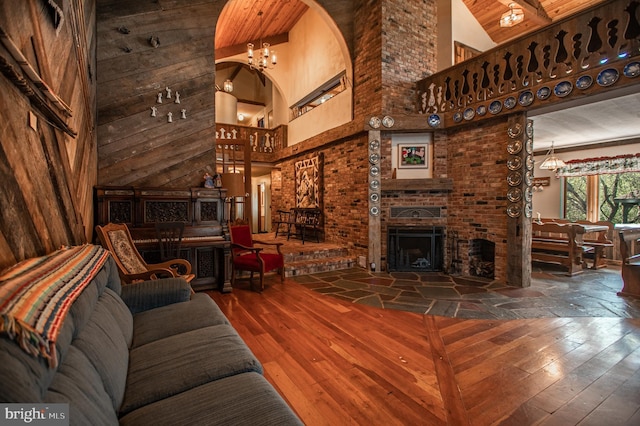 living area with a brick fireplace, a high ceiling, a notable chandelier, and hardwood / wood-style floors