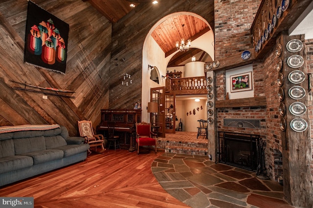 interior space featuring wood walls, a fireplace, hardwood / wood-style floors, high vaulted ceiling, and wooden ceiling
