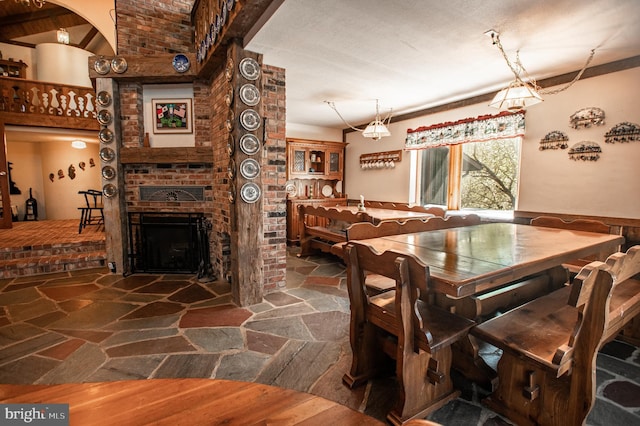 dining room with stone flooring and a brick fireplace