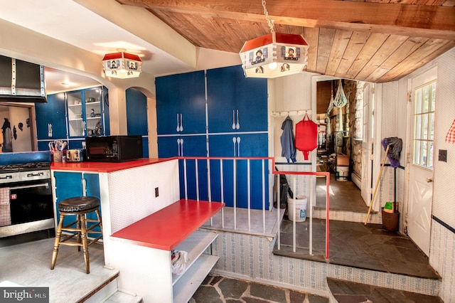 kitchen featuring black microwave, wallpapered walls, wood ceiling, gas stove, and blue cabinetry