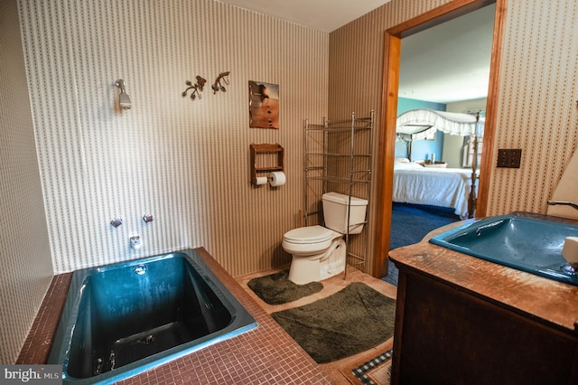 bathroom featuring toilet, wallpapered walls, a tub, and ensuite bathroom