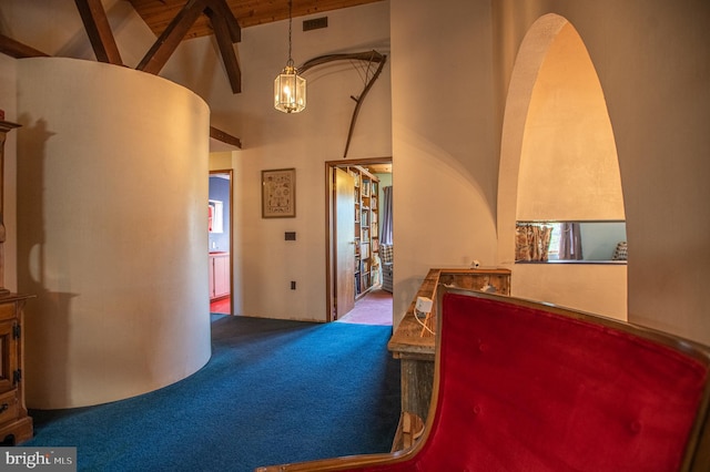 interior space with beam ceiling, carpet floors, arched walkways, high vaulted ceiling, and a chandelier