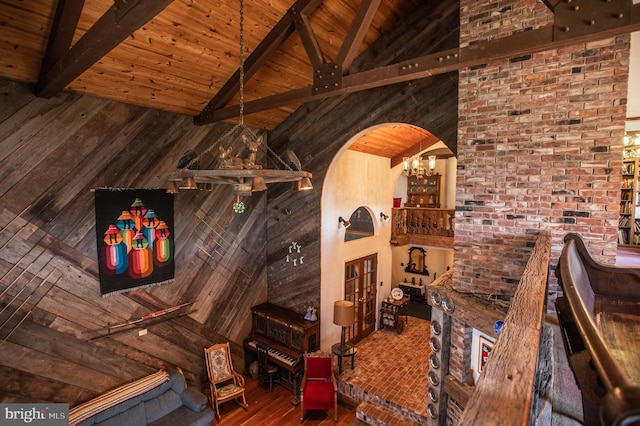 interior details featuring an inviting chandelier, beam ceiling, arched walkways, wooden ceiling, and wood finished floors