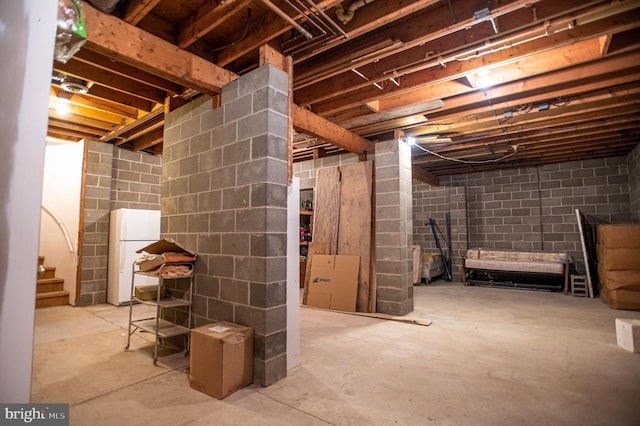 unfinished below grade area with freestanding refrigerator and stairway