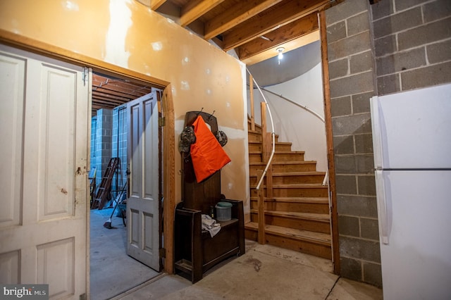 unfinished below grade area featuring stairway and freestanding refrigerator