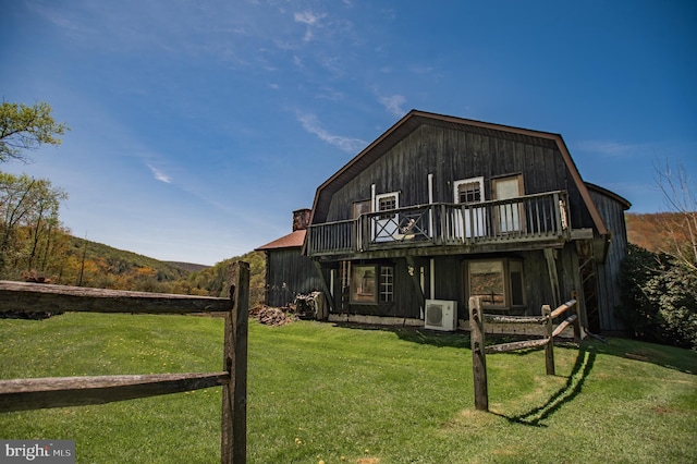 back of property with a lawn, ac unit, a gambrel roof, and a deck