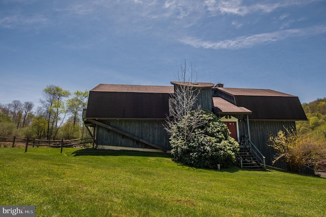 exterior space featuring a lawn, a gambrel roof, fence, and a barn