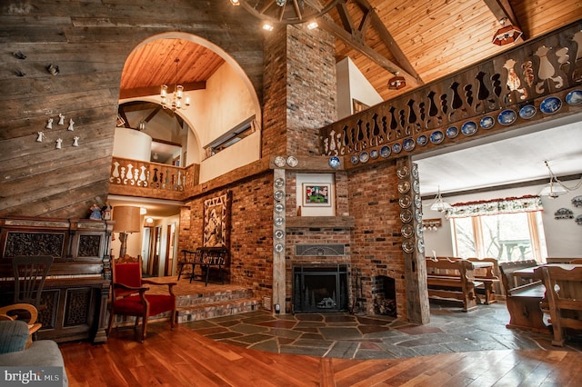 living room with beam ceiling, a fireplace, hardwood / wood-style floors, high vaulted ceiling, and wooden ceiling