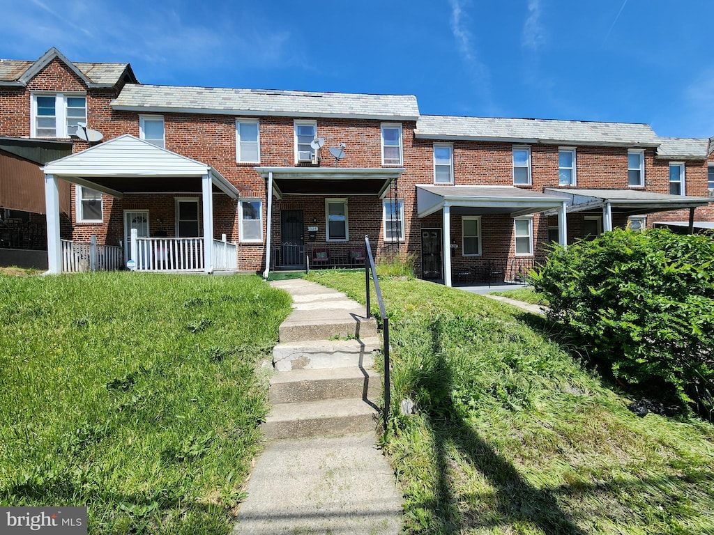 townhome / multi-family property with brick siding, a high end roof, and a front yard