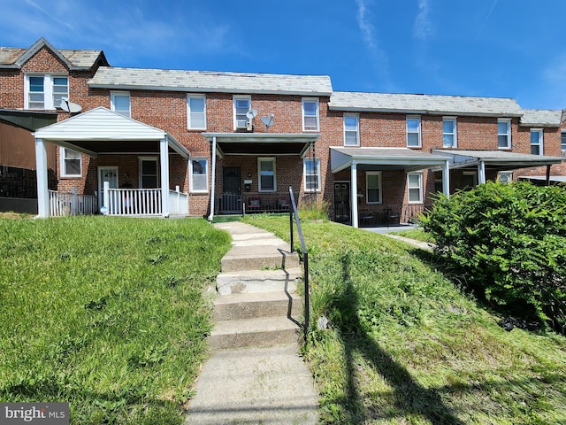 townhome / multi-family property with brick siding, a high end roof, and a front yard