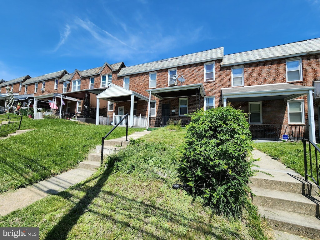 view of front of property featuring brick siding, a high end roof, and a front lawn