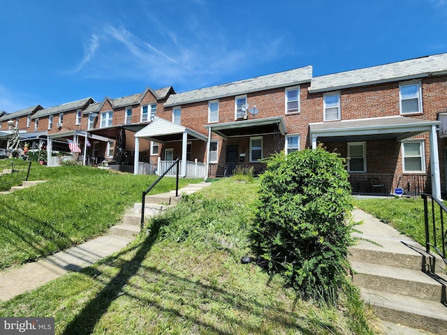 view of front of property featuring brick siding, a high end roof, and a front lawn