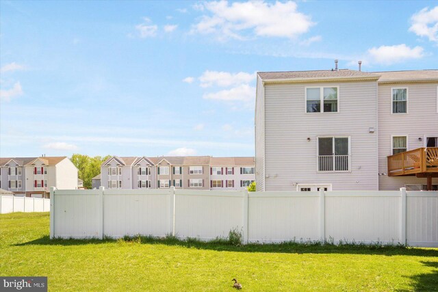 back of house featuring a lawn, fence, and a residential view