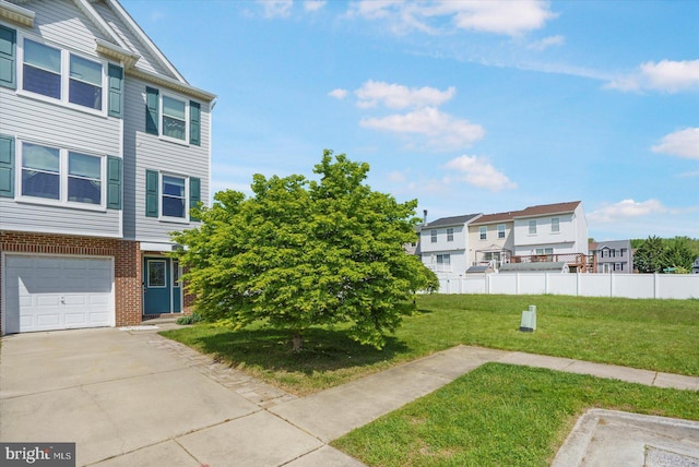 view of yard with an attached garage, fence, a residential view, and driveway