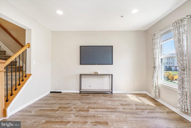 unfurnished living room featuring light wood-style floors, recessed lighting, baseboards, and stairs