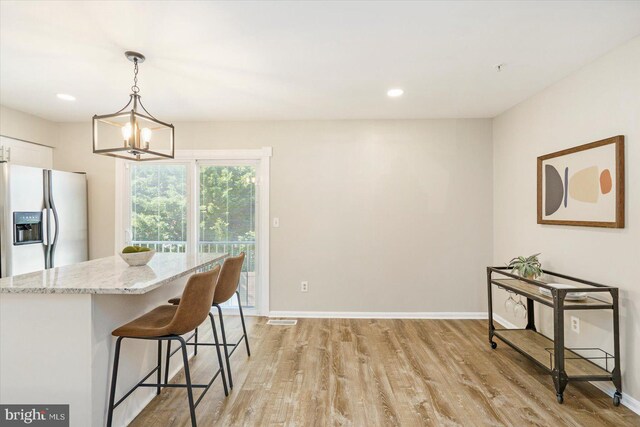 kitchen featuring visible vents, light stone counters, fridge with ice dispenser, white cabinets, and light wood-style flooring