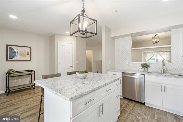 kitchen with stainless steel dishwasher, a notable chandelier, a sink, and a kitchen bar
