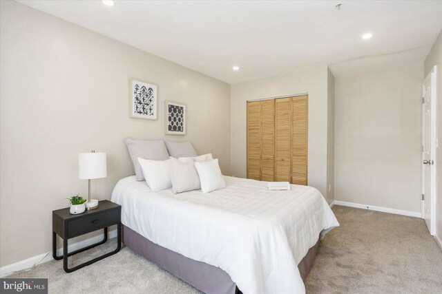 bedroom featuring baseboards, a closet, recessed lighting, and light colored carpet