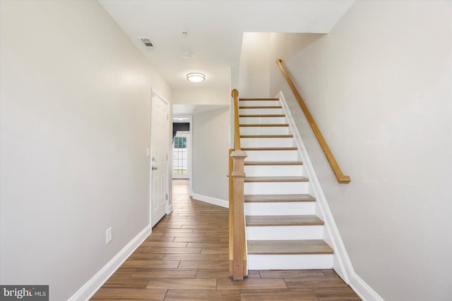 stairs with baseboards, wood finished floors, and visible vents