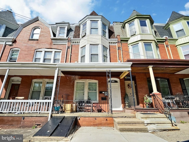 view of property with a porch and brick siding