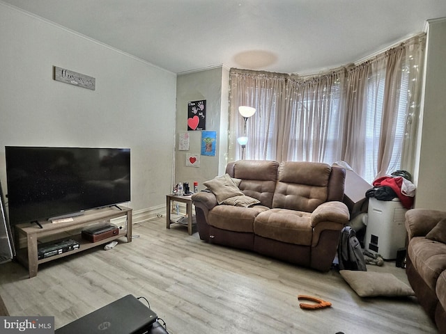 living area with baseboards, ornamental molding, and wood finished floors