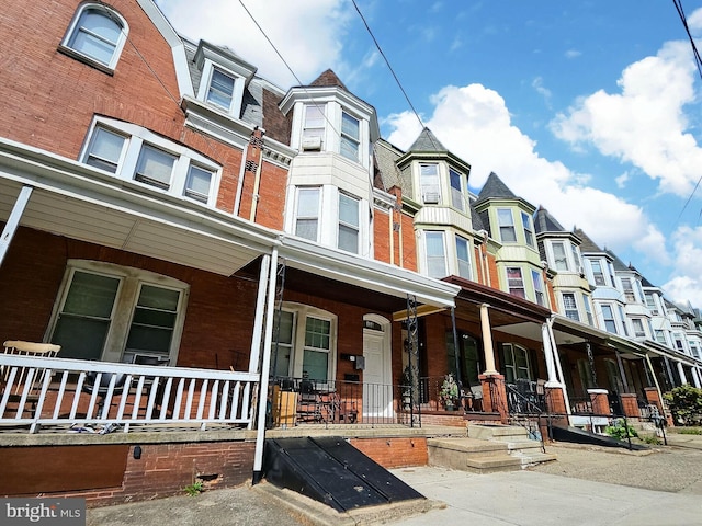 view of front of house with a residential view, covered porch, and brick siding