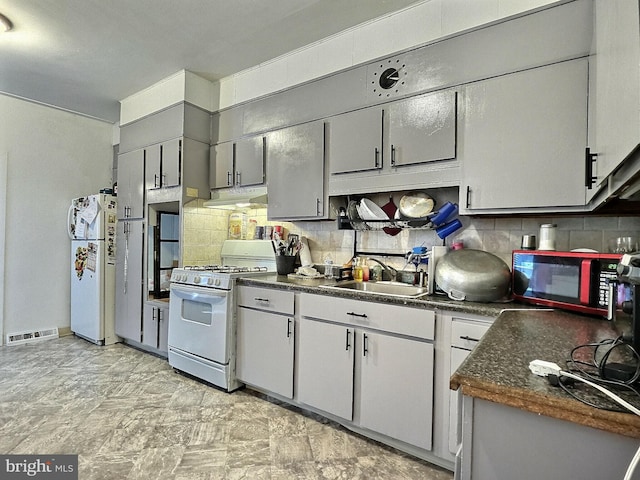 kitchen with visible vents, dark countertops, white appliances, ventilation hood, and a sink