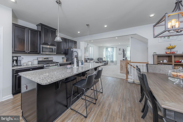 504 Sammy St, Woolwich Twp, NJ 08085 - kitchen with light stone countertops, open floor plan, an island with sink, a kitchen bar, and appliances with stainless steel finishes
