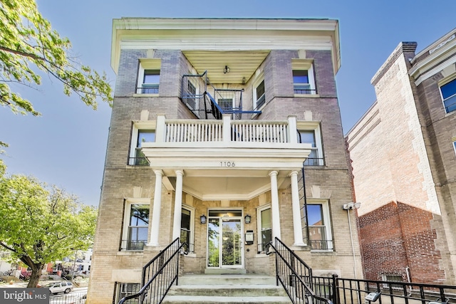 exterior space featuring brick siding and a balcony