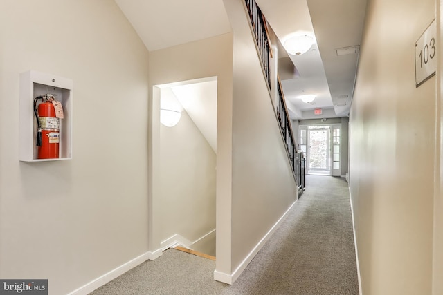hallway featuring stairway, carpet floors, and baseboards