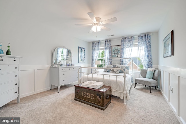 bedroom with a wainscoted wall, light carpet, and visible vents
