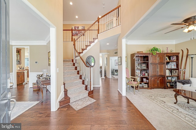foyer with crown molding, hardwood / wood-style floors, ceiling fan, stairway, and recessed lighting