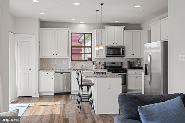 kitchen with a center island, white cabinets, stainless steel appliances, and open floor plan