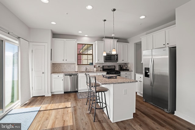 kitchen with a breakfast bar area, white cabinetry, appliances with stainless steel finishes, and decorative backsplash