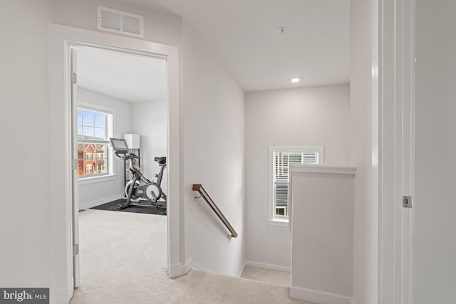 corridor with visible vents, carpet, baseboards, and an upstairs landing