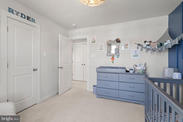 bedroom featuring visible vents, baseboards, a nursery area, and light colored carpet