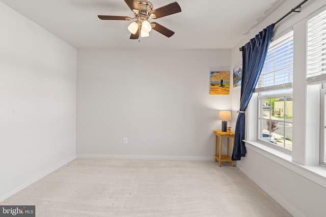 carpeted empty room featuring baseboards and a ceiling fan