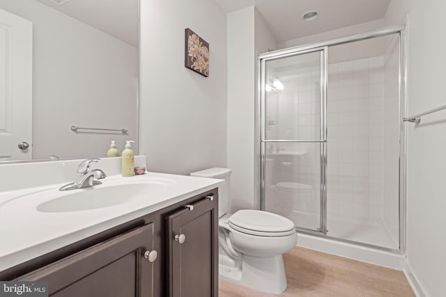 full bathroom featuring toilet, a shower stall, wood finished floors, and vanity