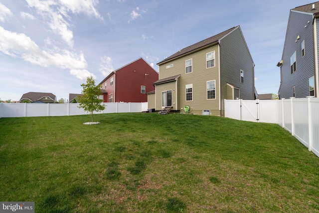 back of house with a yard, a gate, a fenced backyard, and entry steps