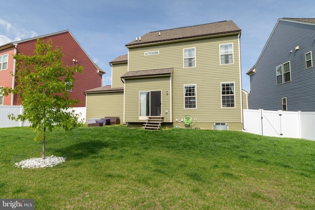 back of house with a lawn, a gate, a fenced backyard, and entry steps