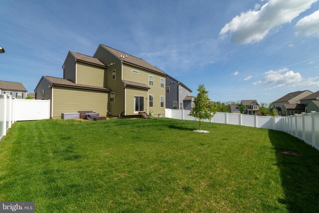 back of house featuring entry steps, a yard, a fenced backyard, and a residential view
