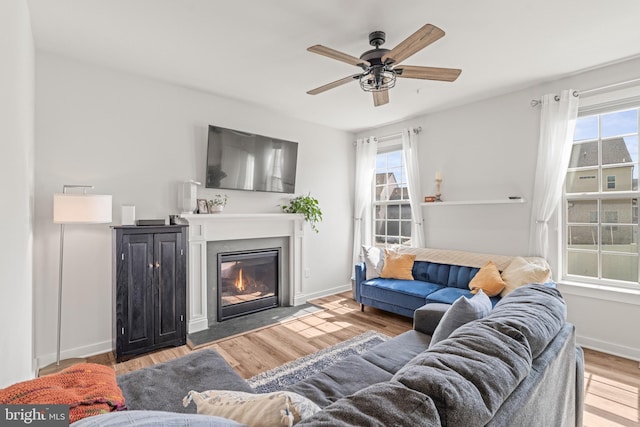 living room with a glass covered fireplace, a healthy amount of sunlight, and wood finished floors
