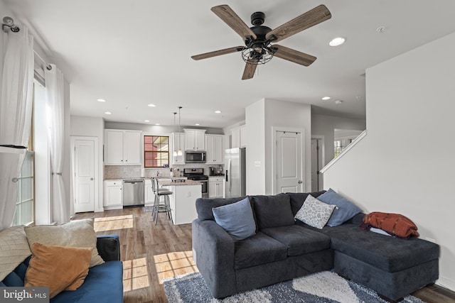 living area featuring a ceiling fan, recessed lighting, and wood finished floors