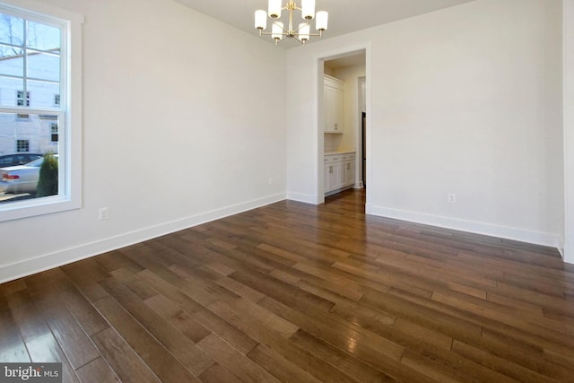 unfurnished room with baseboards, dark wood-style flooring, and a chandelier