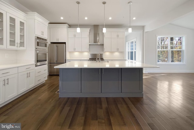 kitchen featuring light countertops, stainless steel appliances, dark wood finished floors, and wall chimney exhaust hood